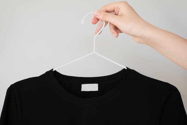 holding black t-shirt on hanger